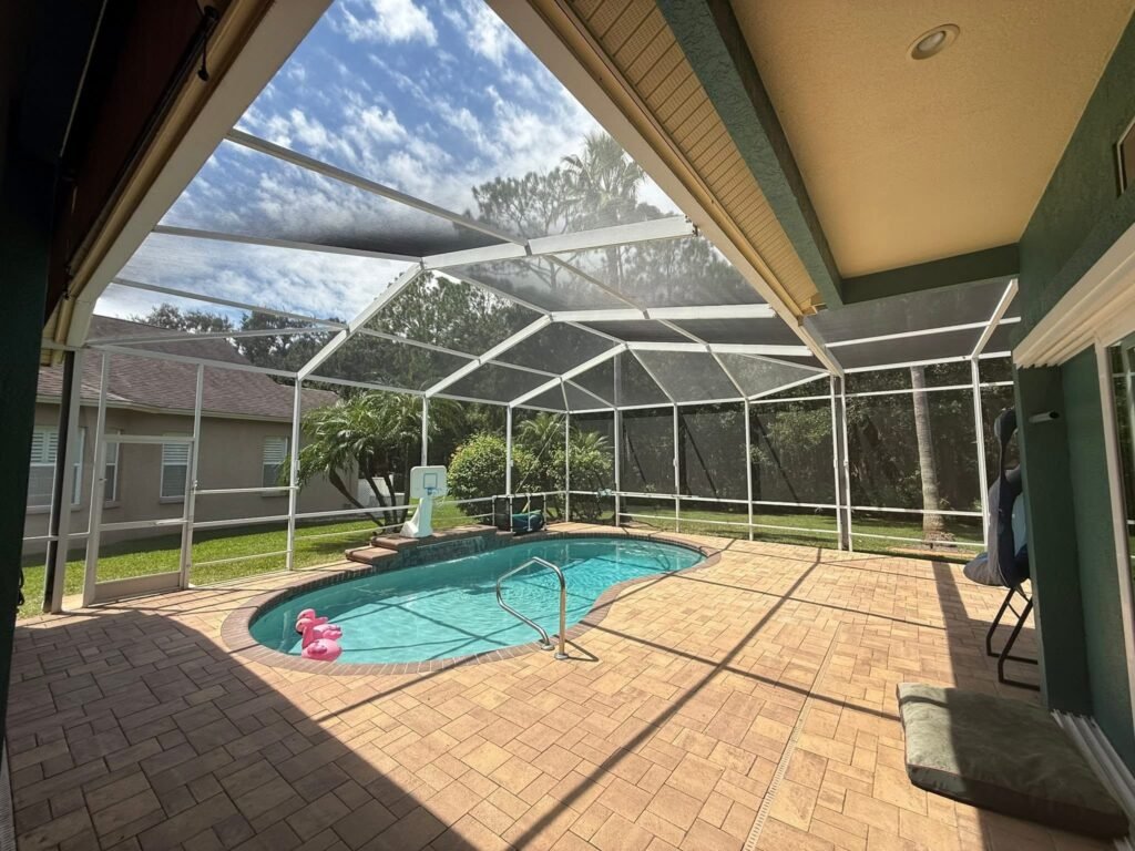 Pool enclosure installation in Fort Pierce, FL surrounding residential backyard swimming pool